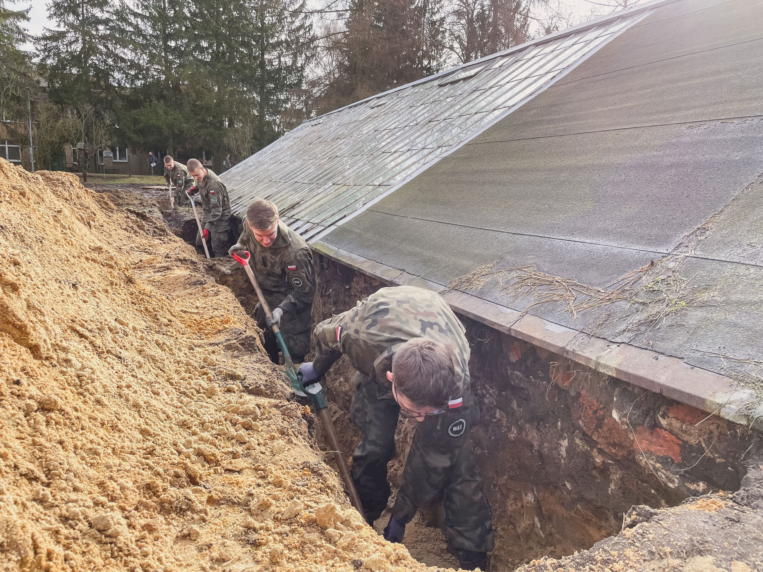 Żołnierze-studenci odkopują fundamenty szklarni.