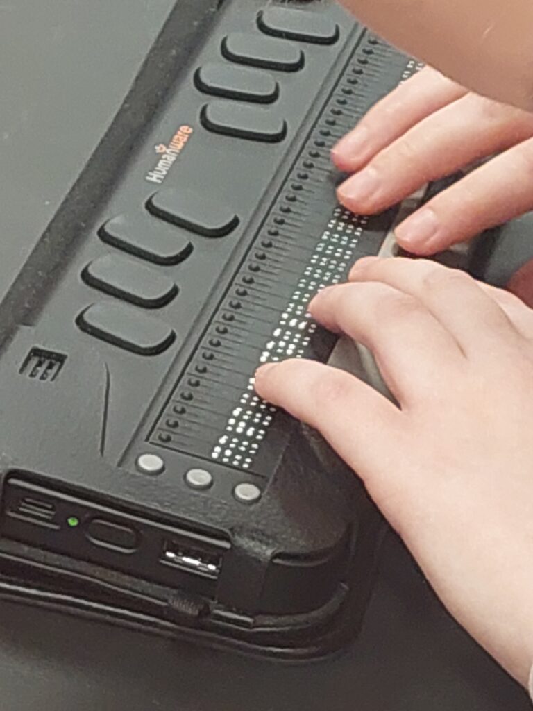 uczeń czyta tekst brajlowski na monitorze brajlowskim